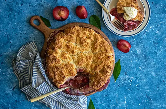 Red Spoonful Of Plum Cobbler against a blue background