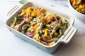 Creamy green bean casserole with mushrooms, red onion, herbs, and a golden crispy topping.